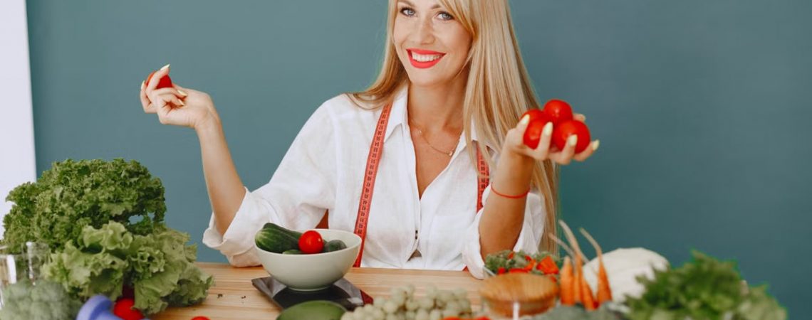 Healthy lifestyle concept with woman holding tomatoes and surrounded by fresh vegetables in a studio setting.