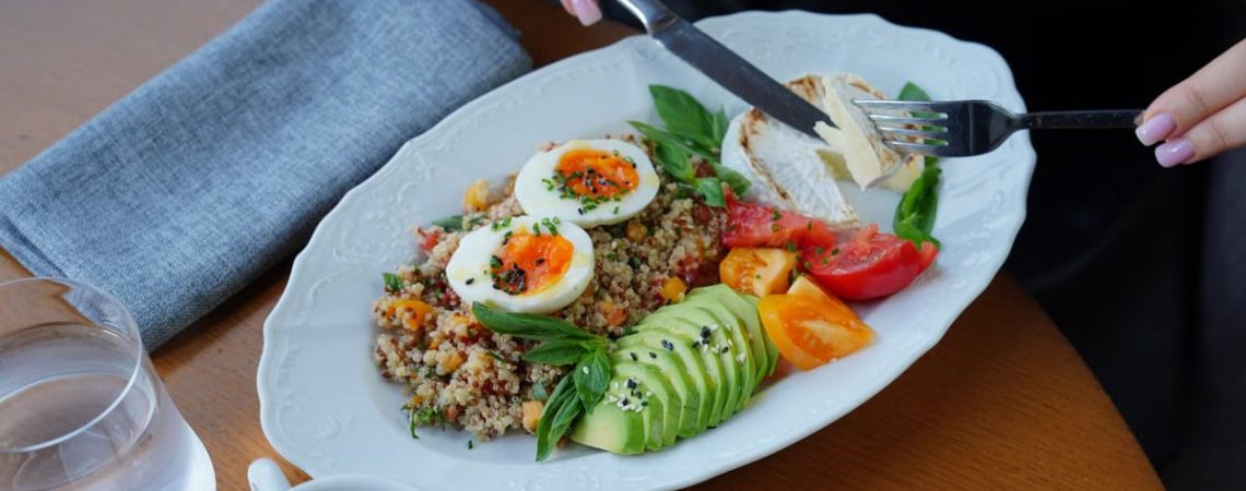 A delicious and healthy breakfast featuring avocado, eggs, and coffee served on a wooden table.